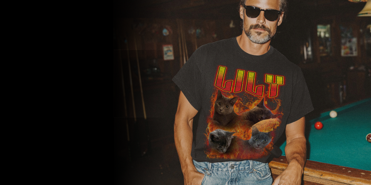 A man wearing a black graphic t-shirt with a fiery red and yellow 'Lil' Y'Ght' design, paired with blue jeans, standing in a dimly lit pool hall next to a green pool table.