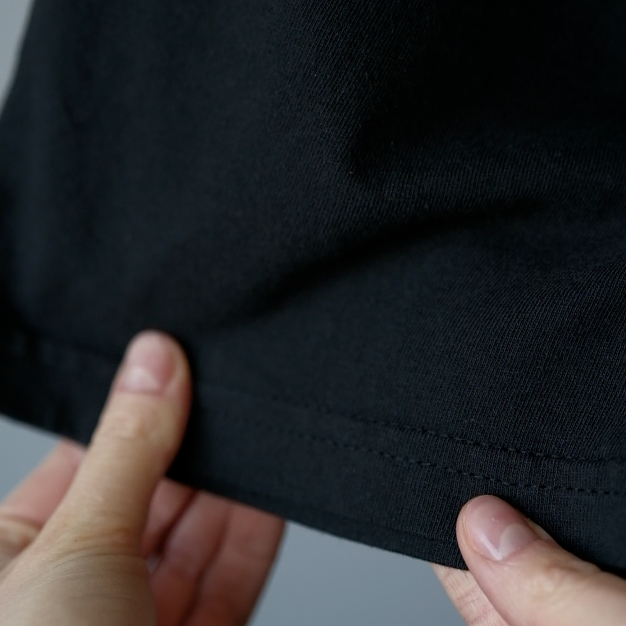 Video showing close-up details of a black T-shirt, including the fabric texture, stitching, and overall finish.